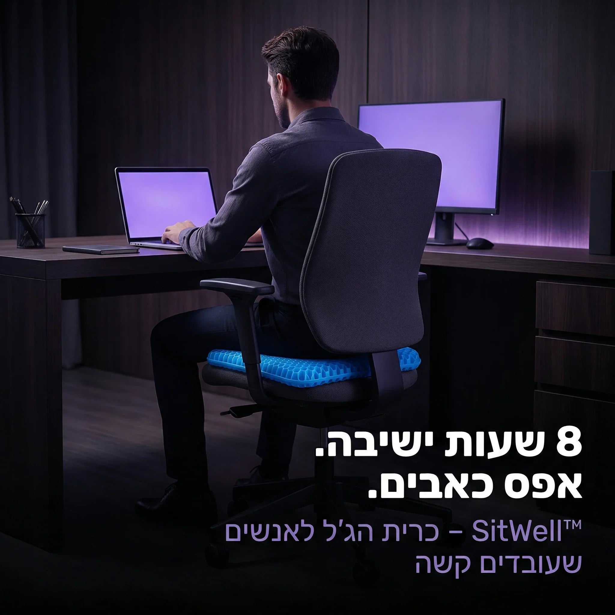 גבר יושב על כיסא משרד עם כרית ג'ל ארגונומית, עובד ליד מחשב במשרד מודרני